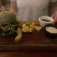 Carrot, beetroot, lentil burger 🍔 in a spinach bun with vegan cheese, sauces and roasted potatoes   at La Hoja Verde in Tulum