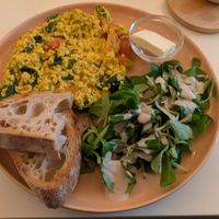 Scrambled tofu with fresh cherry tomatoes spinach, and little side salad with tahini dressing and bread at Vegan Vibes in Berlin