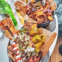 [May 2023] Dutch special (vegan). Spicy ketchup, mayo, onion mix, jewish pickles, nutmeg crumble.
In the backgroud: Mideast (vegetarian). at Pom Friterie in Stockholm