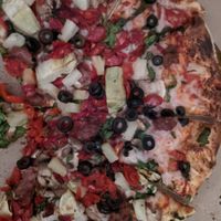 Pizza red sauce, beyond meat, vegan cheese, olives, spinach, artichokes, tomatoes, pineapple, peppers, mushroommmmmms at Leonardo's Pizza in Burlington