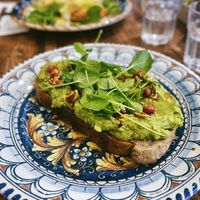 Vegan avo sourdough toast with a generous topping of avocado, chili nut oil, dukkah, and watercress. at Society Bar & Kitchen in Edinburgh