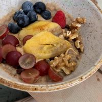 Porridge con chips de chocolate, mantequilla de cacahuete, canela, plátano sellado, frutas frescas, nueces tostadas y sirope 🍇🍓🫐🍌  at La Aldea Cafe Bar in Conil De La Frontera