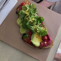 Tostada con hummus de remolacha y hierba buena, aguacate, tomates cherry, canónigos y rawmesan 🥑🍅  at La Aldea Cafe Bar in Conil De La Frontera