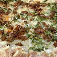 Closeup of The Corleone with vegan sausage, vegan cheese, garlic, arugula, EVOO, chili crunch and GF crust 💚  at Saint Paul Brewing in St Paul
