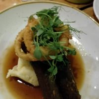 Seitan sausages, potato puree and onion rings at The Green Rocket Cafe in Bath