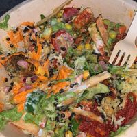 Grains bowl with basmati rice, black lentils, red pepper hummus, falafel, tomatoes, cucumbers, pita crisps, corn, harissa hummus, skhug dressing  at CAVA in Fredericksburg