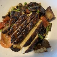 Seared tempeh on a bed of roasted potatoes, asparagus, mushroom, tomatoes and peas.  at South Kitchen + Spirits in Ponte Vedra