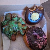 Apple fritter (Green for St. Patrick's), Boston creme, & strawberry glaze + Oreo topping. All yeasted. at Just Fine Donuts in Alexandria