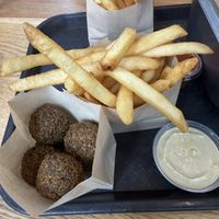 Balls in a bag with mild tahini sauce and sides of fries inside  at Goldie - Midtown in Philadelphia
