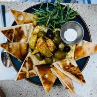Hummus Olives marinées chaudes, artichaut, zeste d'orange, naan at Les Mauvaises Herbes in Quebec