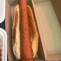 Hotdog with mustard/ ketchup and sauerkraut in container on the side.  at Neat Burger - Wembley in North West London