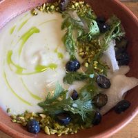 Chilled Kohlrabi Soup with pistachio, fig leaf oil, pickled blueberries, and shungiku.   at Feral in Portland