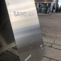 The shiny sign across the street pointig to the deli on the corner in the distance. at Saint-Jean Deli in Amsterdam
