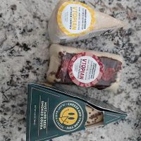 showcases v topian smokey cheddar, v topian dark chocolate strawberry brie, and mustard seed smoked gouda. at Vtopian Cheese Shop in Portland