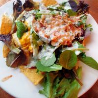 Nachos ~ Black Bean Chili, (vegan) Creamy Cheddar Cheese Sauce, Fresh House Salsa, Greens, Topped with a Swirl of Ranch.  at Kitchen 17 in Chicago