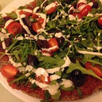 Raw vegan pizza with rocket, black olives and cashew dressing at Secret of Raw in Prague