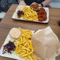 Two plates featuring Just Vege's dishes: Hummus & Falafel Pita with gluten free pita bread; Vegan meatballs with bean salad, both dishes came with fries. at Just Vege - Forum in Helsinki