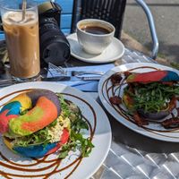 Rainbow bagels (sun-dried tomato & feta, and scrambled tofu). Rainbow bagels are optional! Also an iced coffee, and a black coffee at Pip & Oat in Llandudno