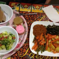 Main plate has: Gomen dish, Yatkilt dish, Fasolia dish, & a Greenbean dish
 Side plate has: Strawberry cupcake (gf), Timatam salad, & gf injera at Azla Vegan in Los Angeles