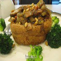 Hot pot of vegetables and mock meat garnished with pine nuts, in edible bowl of taro at The Original Buddha Bodai - Kosher Vegetarian Restaurant in New York City
