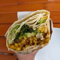 Vegan burrito - bitten. Fillings include greens, white beans, bulgar rice, caramelized onions, avocado, sauce at Overhang Oven in Antalya
