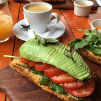 Savoury breakfast: Roasted bread with herbs topped with rucola (arugula), tomato and avocado, served with a tomato sauce on the side and a fresh juice and coffee at Green Point in Cusco