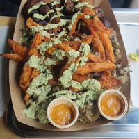 XL portion: jollof rice with chickpeas, Yassa sauce, plantains and Cajun sweet potato fries, plus extra green sauce and chili sauce at Osè African Cuisine  in Paris