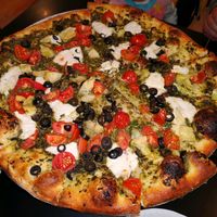 Pizza with pesto, vegan mozzarella, tomatoes and black olives at Flying Saucer Pizza Company in Salem