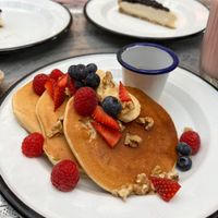 Gluten free vegan pancakes with almond milk, orange zest, orange blossom and maple syrup. Served with fresh bananas, fresh mixed berries and walnuts.  at Comptoir 102 in Dubai