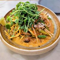 Shiitake Peanut Laksa: red chilli coconut broth, stir fried shiitake tender stem broccoli, noodles, chilli oil, crushed peanuts, fragrant herbs at Mildreds - Victoria in South West London