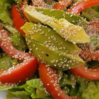 Appetiser salad contains avocado, tomato and lettuce with sesame seeds and a light dressing at Amaranta Cocina Consciente in Medellin