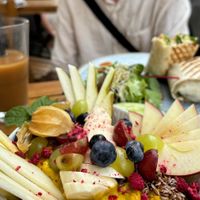 Golden porridge with berries and fresh fruit. Chikken (vegan) wrap in the background.  at V-Cake Cafe in Dresden