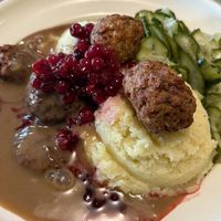 Two large scoops of mashed potatoes, cucumber salad, vegan meatballs, gravy sauce, and cranberry sauce  at Möllers Köttbullar - Danziger Str. in Berlin