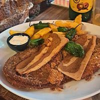 Cachopo vegano con bacon plant based, patatas y pimientos de Padrón at Con 2 Fogones in Madrid