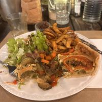 (Sorry I already started eating it) This is the Assiette Végé. It's an egg tart with leek, tomato and parsley, side of chips; salad; cooked veggies and cartelised onions.   at L'Aloko Restaurant - Café Concert in Millau