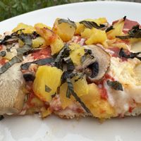 2 slices of 10” Vegan grandma pizza with mushrooms & pineapple with thin julienned slices of fresh basil on top.  at Genova Pizza in Audubon