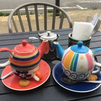 Two colourful teapots stacked inside matching cups on a table at a roadside cafee  at Driftwood Cafe in Wallasey