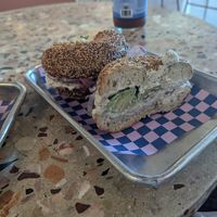 toasted sesame seed bagel with vegan cream cheese onions (raw and pickled) radish and avocado at Flour Moon Bagels in New Orleans