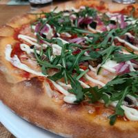 Pizza with rucola on top. at Rosso in Tampere