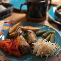 A mix of different vegan dishes, backed potato with onion, plate of pickles and aubergine rolls  at Chinkalnia Restauracja Gruzińska in Gdansk