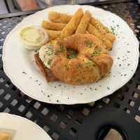 Croissant breakfast sandwich with vegan sunny side up egg and bacon, side of yuca fries  at A Lo Vegano Orlando in Orlando