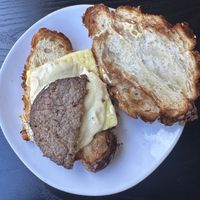 Half of an overcooked burger and a premade just egg omelette square.    at Plant City in Barrington