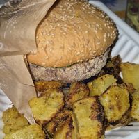 Burger di patate e legumi con bun ai semi di sesamo, condito con mayo all'erba cipollina e insalata di cavola viola e mele. Accompagnato con patate al forno sabbiate. ATOMICO at La Casina di Alice in Livorno