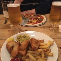 To fish with mushy peas and chips with Korean “chicken” bbq pizza in the background  at Mono in Glasgow