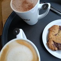 Oat milk latte (btm left), oat milk hot chocolate with vegan marshmallows (top left), choc chip cookie (right middle) at Caffe Nero in Castlebar