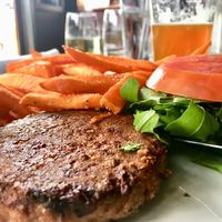 Beyond Meat burger served on a bed of arugula with sweet potato fries  at The Libertine in Dallas