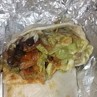 Cut of vegan chicken burrito with lettuce, beans, avo, salsa, veg cheese. at Mad Mex in Wantirna South