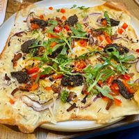 Flammkuchen met  'shpeck' (vegan bacon), truffelsalsa, zoete puntpaprika en rode ui en rucola at Kosmopoliet in Bruges