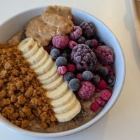 Porridge bowl with chia seeds, banana, frozen berries, biscoff crumb, and peanut butter at blend in Newquay