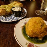 A photo of twob plates with gralic bread with mayo and a big arancini ball. at Segreto in Helsinki
